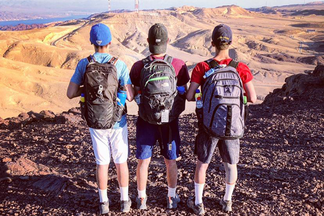 three campers' backs, looking over a mountain view